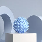 Balle de massage myofasciale PuraDorse Point bleue posée sur un socle, fond gris bleuté