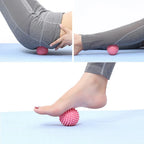 Balle de massage PuraDorse Point rose utilisée sous le pied et le long de la jambe, assis au sol