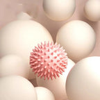 Balle de massage myofasciale PuraDorse Point rose sur un fond de sphères crème