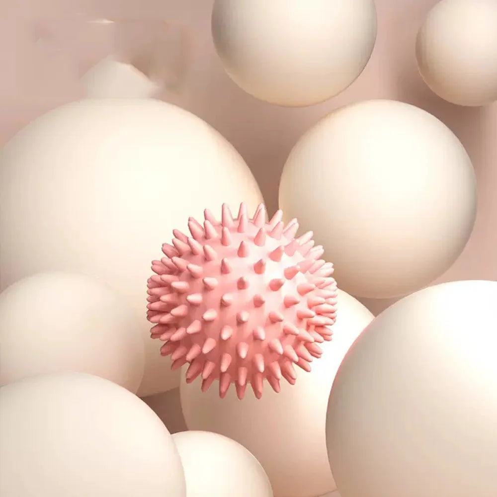 Balle de massage myofasciale PuraDorse Point rose sur un fond de sphères crème
