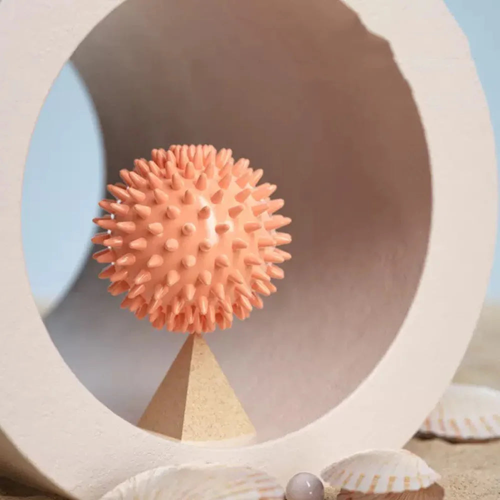 Balle de massage myofasciale PuraDorse Point orange dans un décor minéral clair