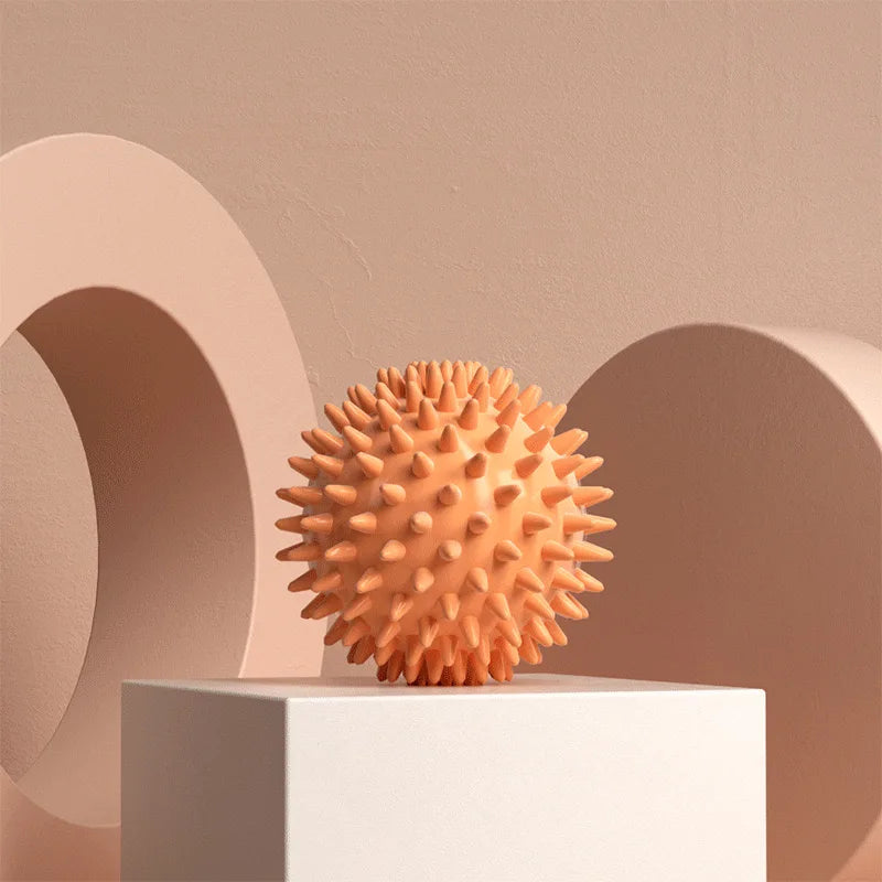 Balle de massage myofasciale PuraDorse Point orange posée sur un socle, fond sable