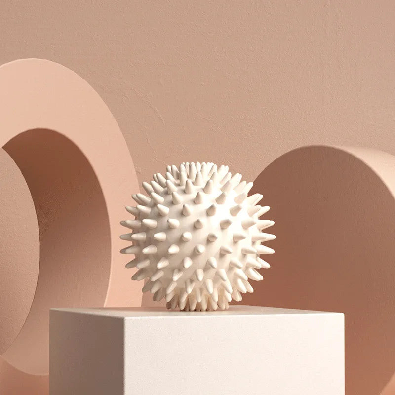 Balle de massage myofasciale PuraDorse Point blanche posée sur un socle, fond rosé